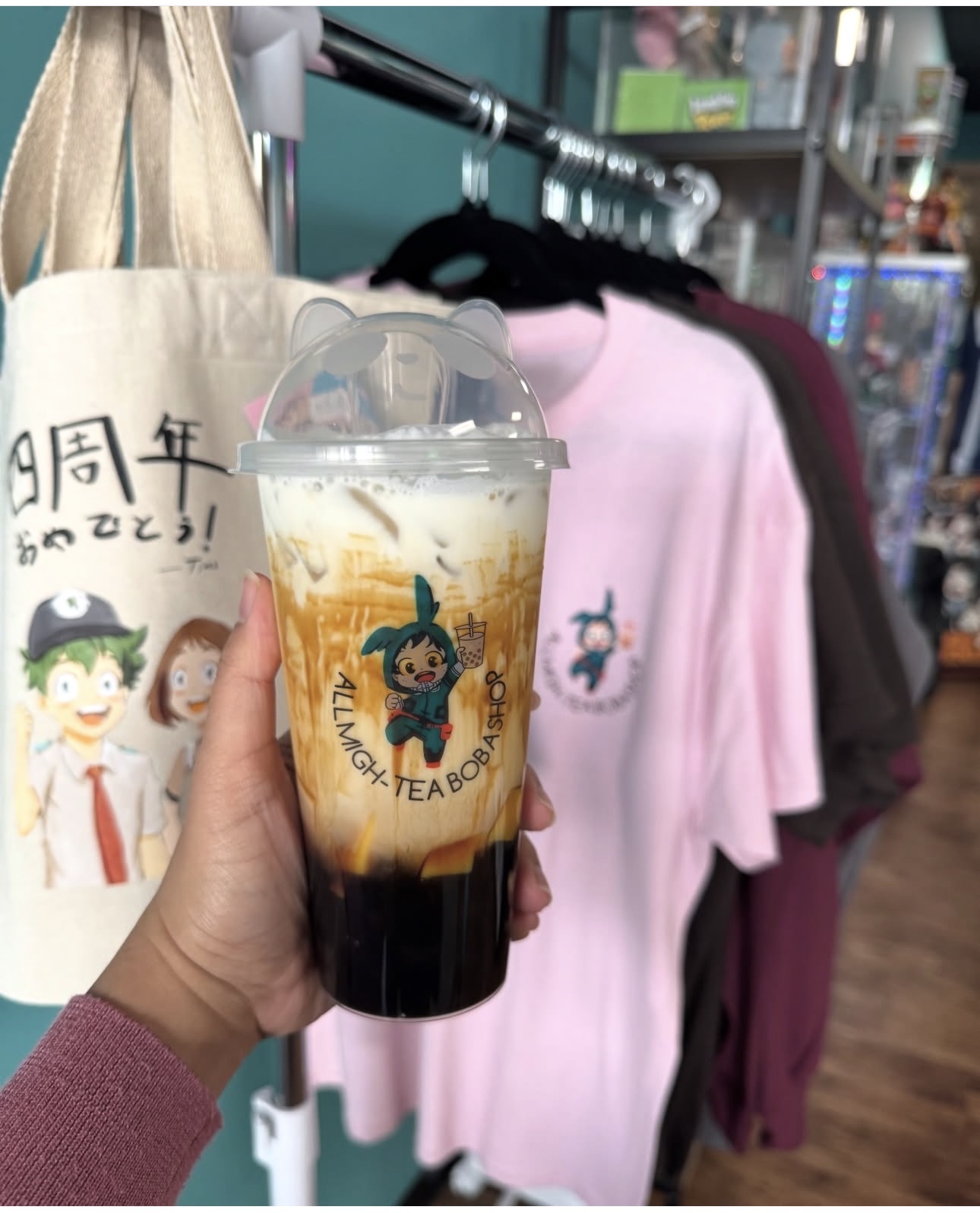 Brown sugar boba held up next to anniversary tote and shirts